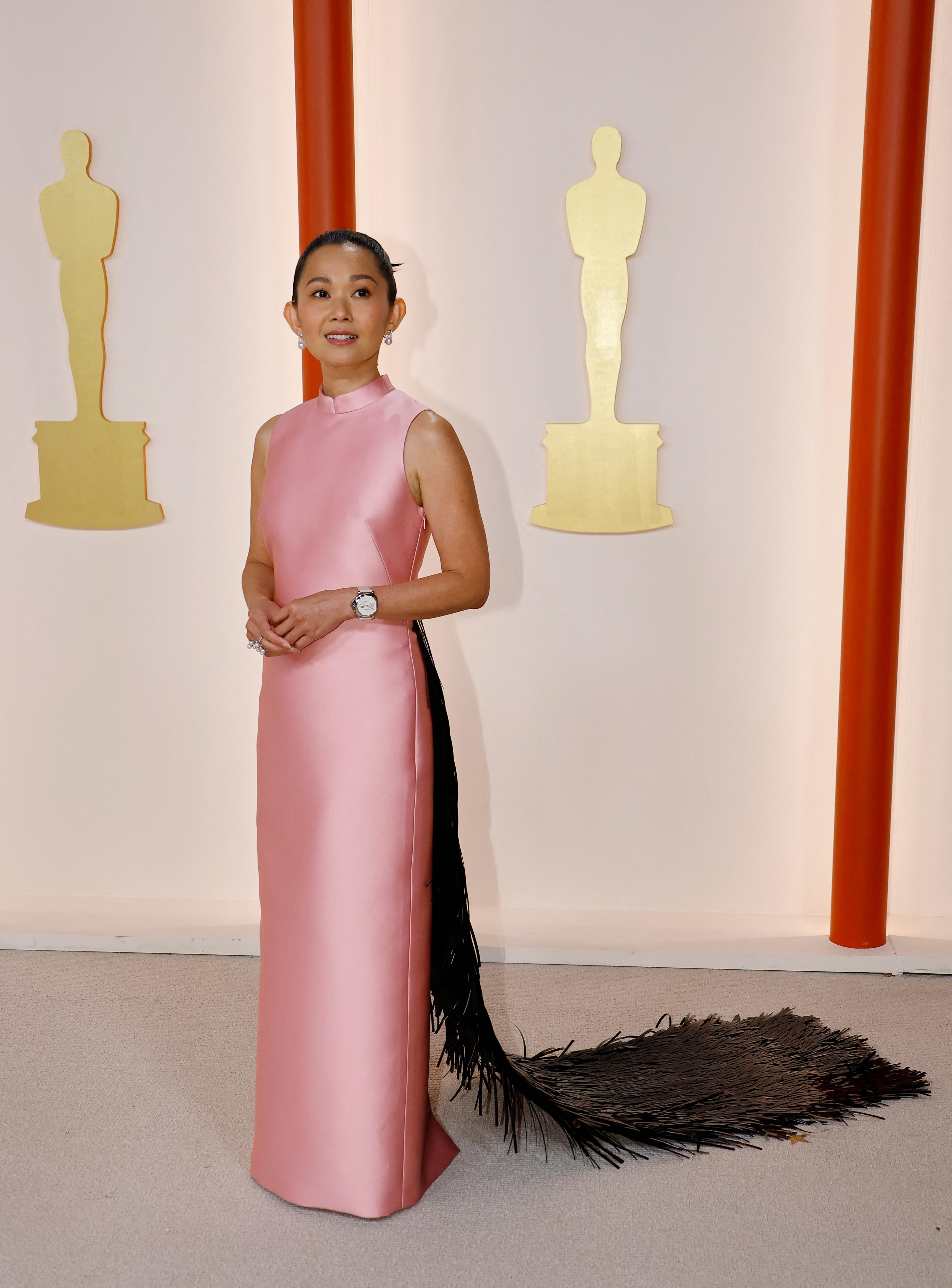 Hong Chau wearing a baby pink high neck sleeveless gown with a dark brown furry-looking train