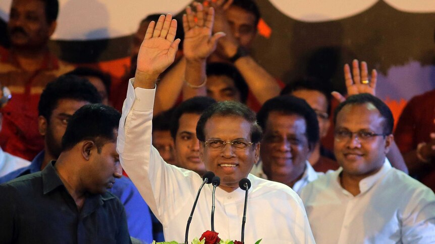 Sri Lankan President Maithripala Sirisena stands at a podium and waves.