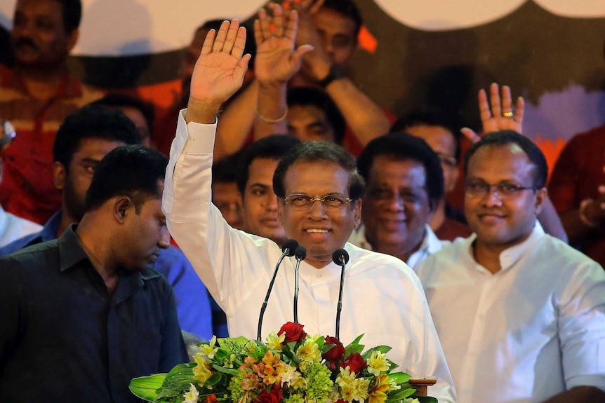 Sri Lankan President Maithripala Sirisena stands at a podium and waves.