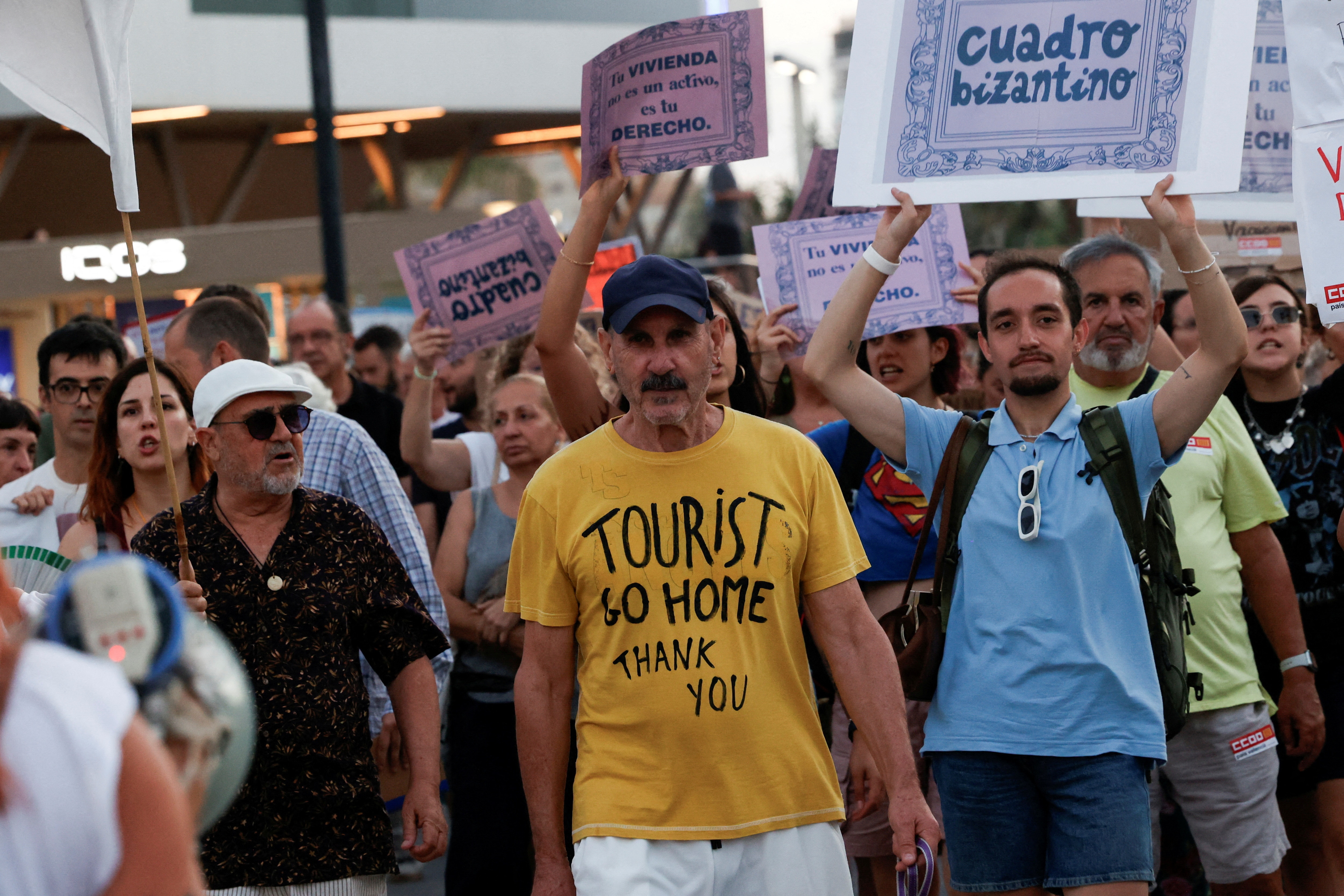 A man wears a shirt reading 'tourist go home'.