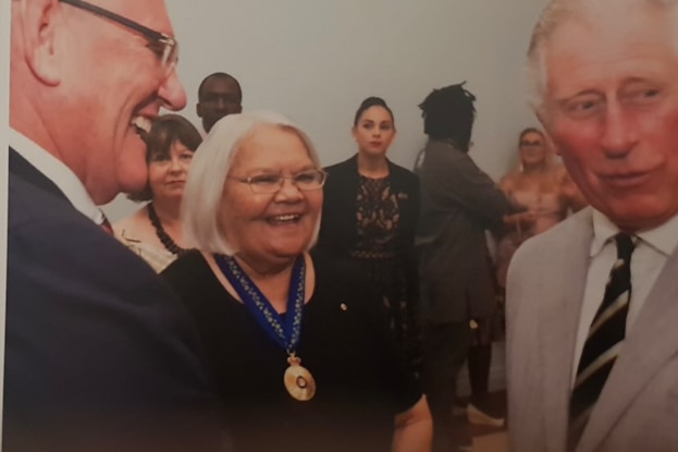 Patricia is standing in the middle of a delegate and King Charles at an event