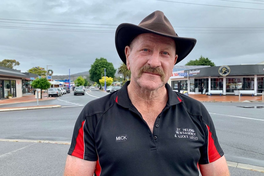 Break O'Day Mayor Mick Tucker stands on a main street with cars and shops in the background.