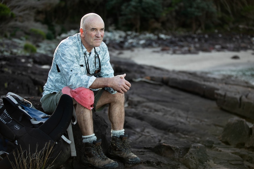 Mick sits on a rock in a cove