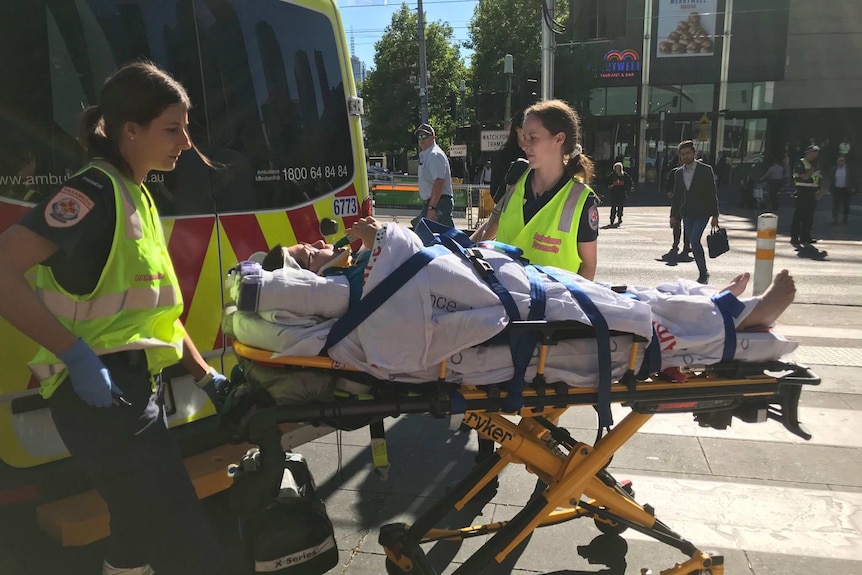 A 23-year-old woman is strapped to a stretcher and is about to be loaded into an ambulance.