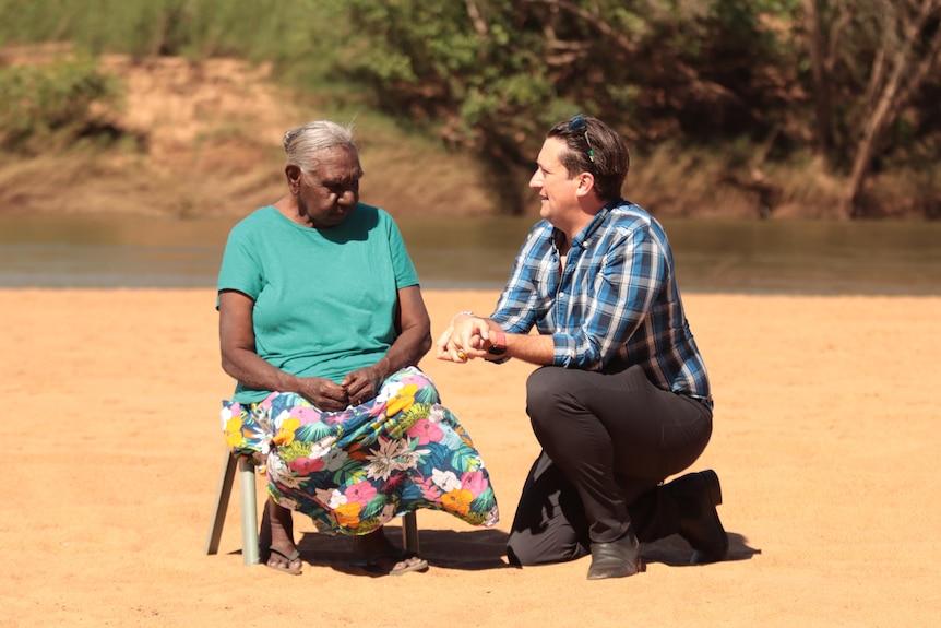 Dan Bourchier kneels down next to Miriam-Rose Ungunmerr Baumann\