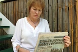 Sam Larkins reads a newspaper showing the headline 'yabulu workers brace for worst'.