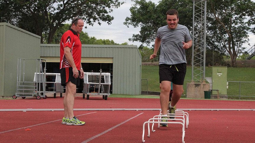 coach and younger person jumping over hurdles