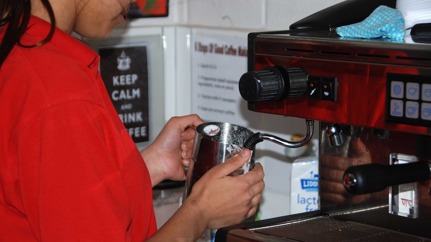 A detainee at Banksia heats milk at coffee machine as she learns how to be a barista, in Perth