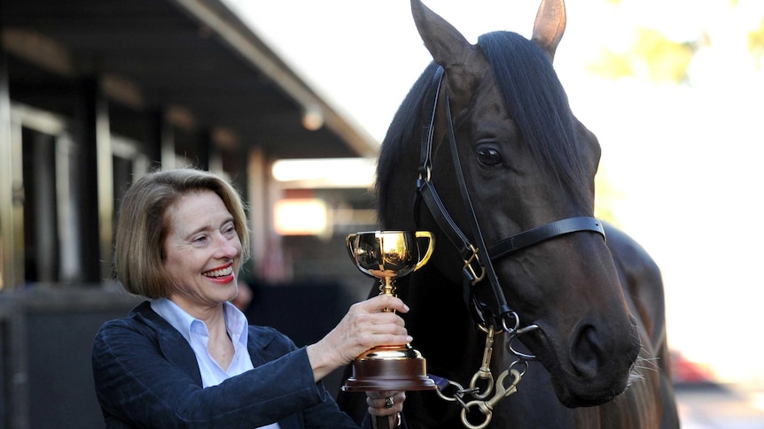 Gai Waterhouse poses for photos with Melbourne Cup winning horse Fiorente and the trainer's trophy.