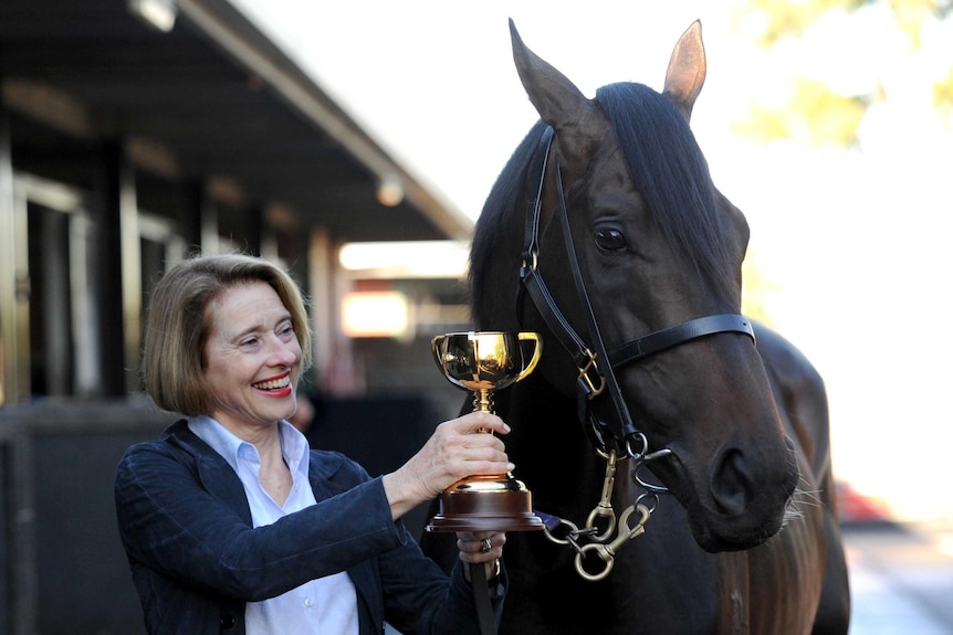 Gai Waterhouse poses for photos with Melbourne Cup winning horse Fiorente and the trainer's trophy.