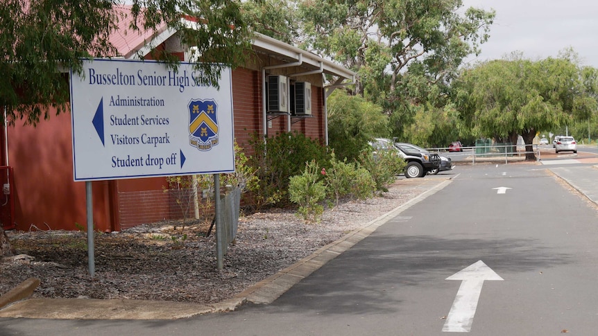 A sign outside of Busselton Senior High School with a building and trees in the background.