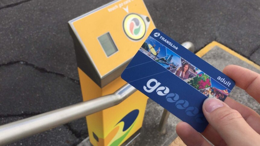 Commuter holding a blue Go Card in front of a "tap on" station.