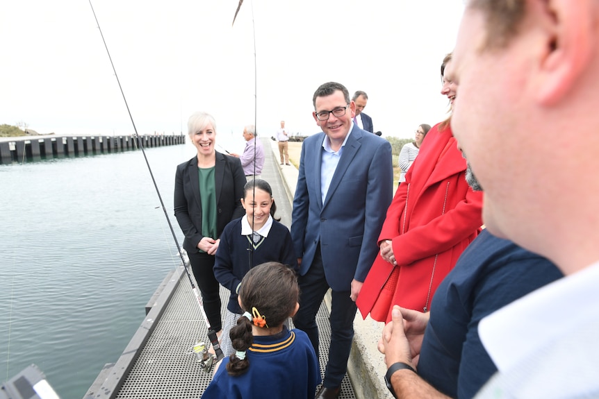 Daniel Andrews smiles next to kids with fishing rods at the Mordialloc pier