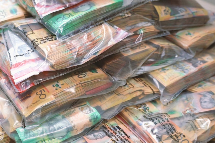 A close-up shot of bundles of $50 and $100 notes in plastic bags.