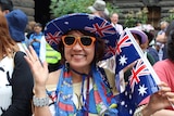 Jamie "from Sydney" grins, wearing an Australian flag hat and holding a small flag.