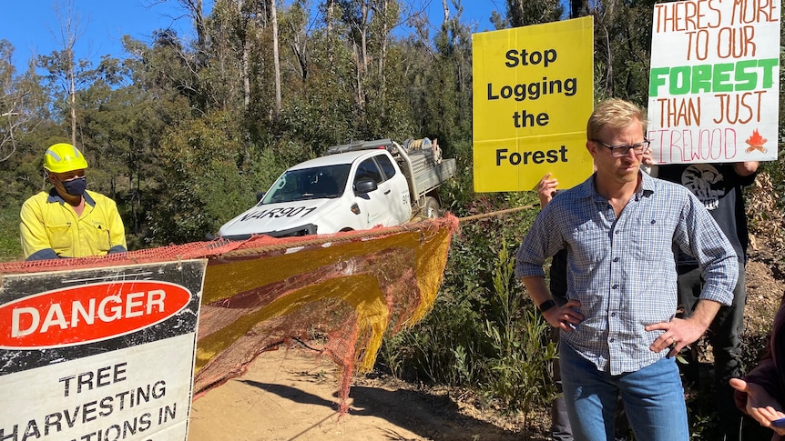 A man and protesters next to a forest barrier