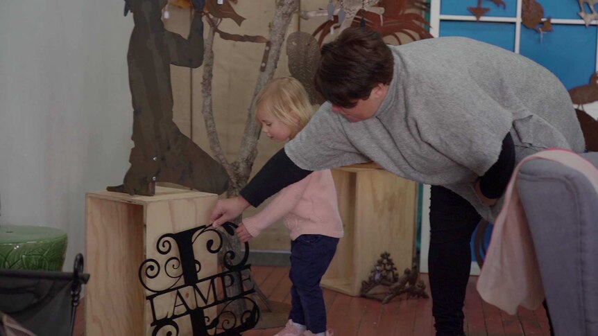 A woman with a young child looking at a piece of metal art
