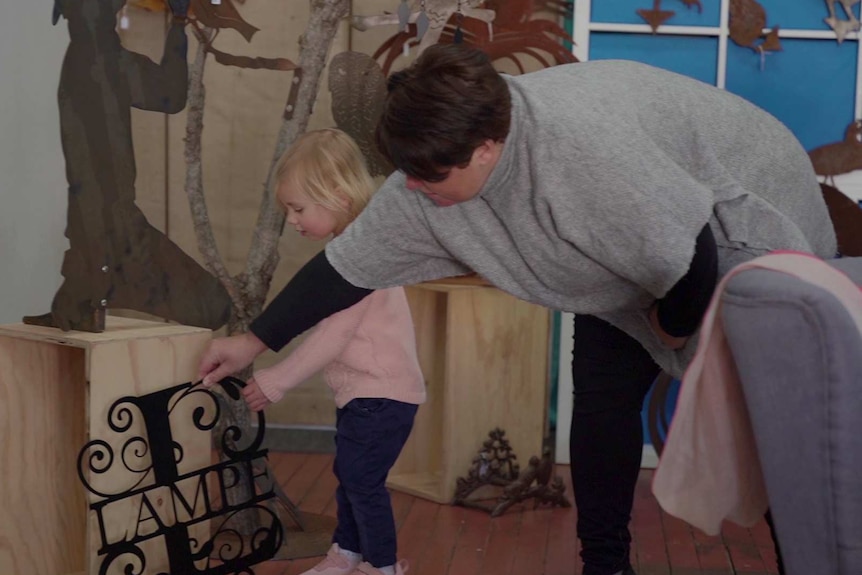 A woman with a young child looking at a piece of metal art