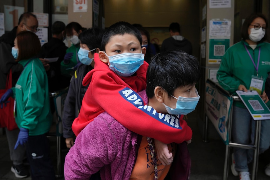 A child wearing a face mask on his father's shoulders. 