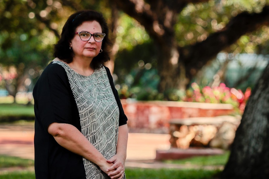 AIDA vice president Simone Raye standing in a public garden, with trees and flowers in the background.