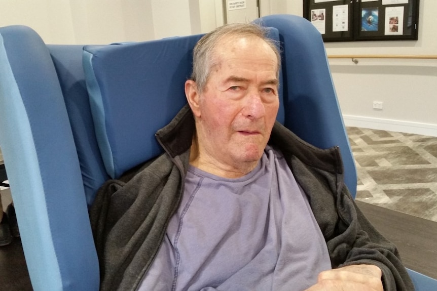 Ernie Poloni sits in an armchair in an aged care facility.