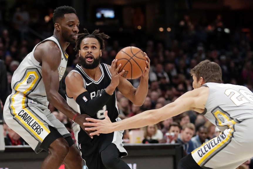 Patty Mills drives for San Antonio Spurs while being defended against by Jeff Green and Kyle Korver of Cleveland Cavaliers.