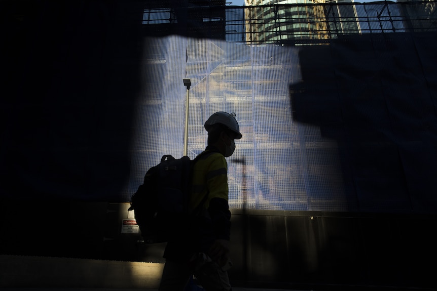 The silhouette of a construction worker at a site.