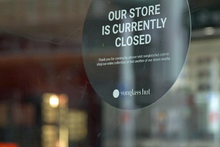 A sign on a glass door says 'Our store is currently closed'.