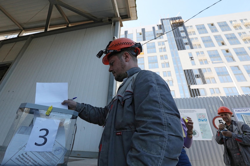 A man puts the ballot paper in a box in referendum to join Russia in uKraine. 