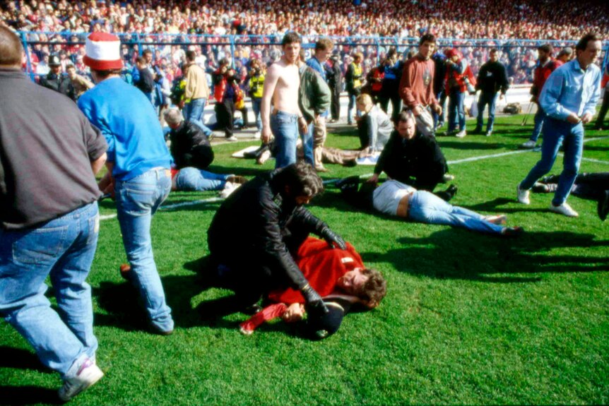 football supporters lay wounded on the pitch at hillsborough stadium as people tend to them