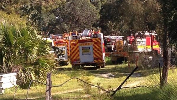In a rural setting with trees, several fire engines are parked after a man died in a tractor accident at Ballajura