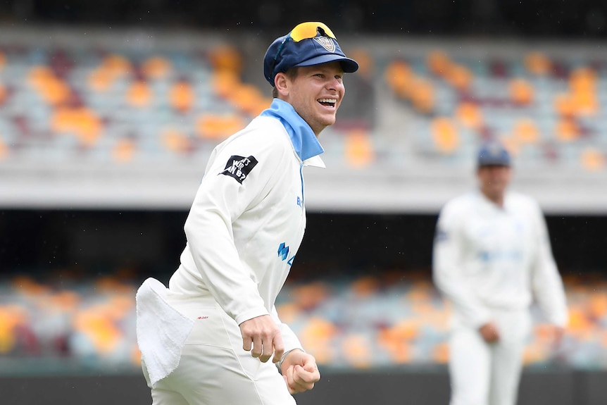 Steve Smith smiles while standing in the field.