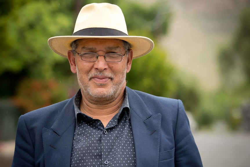 Stephen Smith stands outside wearing a wide brim hat in a portrait photo.