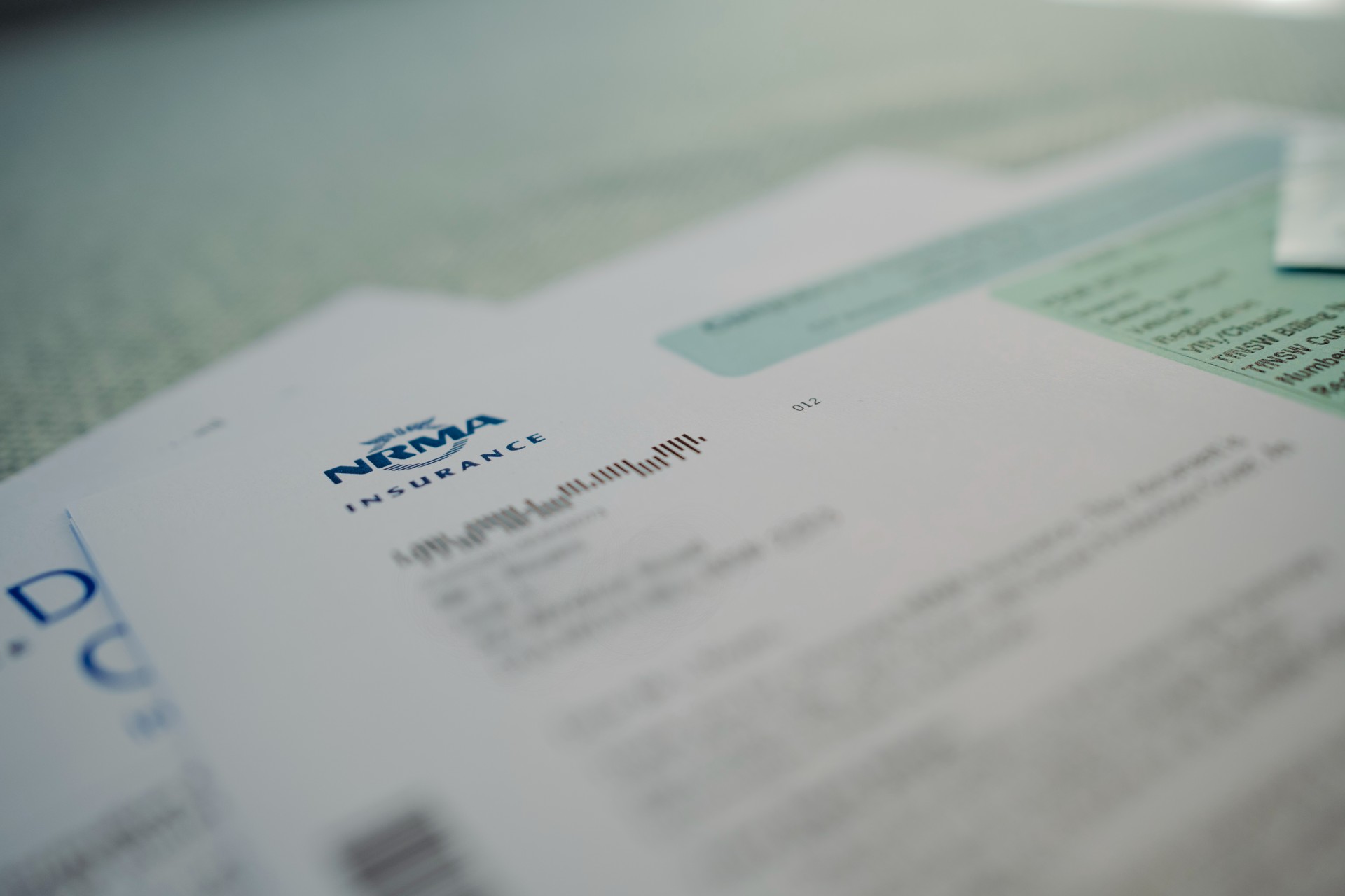 An up close photo of NRMA Insurance paperwork with the name logo in blue, and key private details blurred.