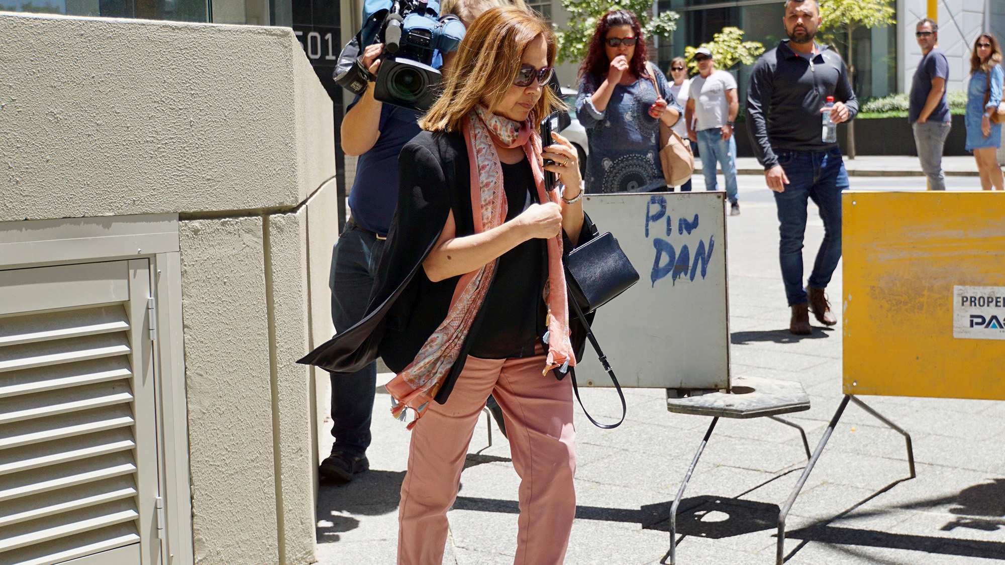 A woman in sunglasses, a black top and apricot pants outside a Perth courthouse.