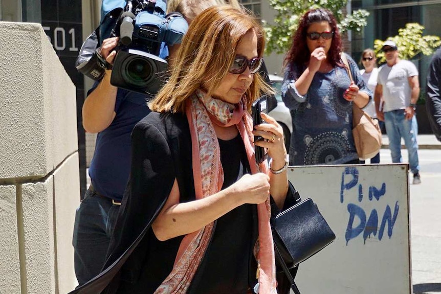 A woman in sunglasses, a black top and apricot pants outside a Perth courthouse.