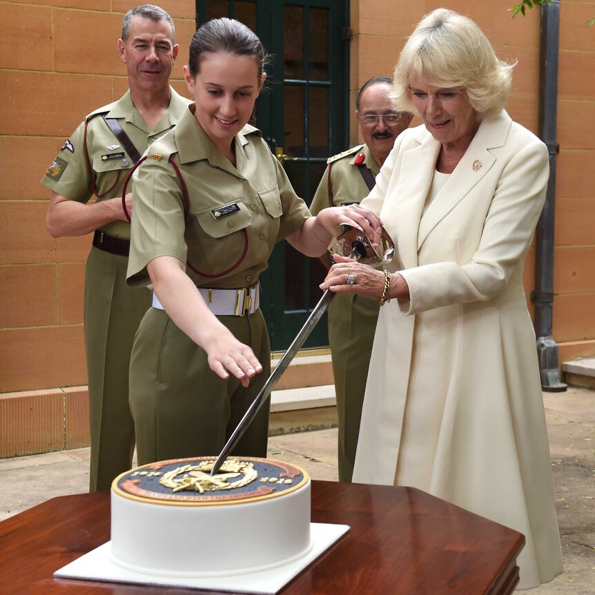 Camilla Duchess of Cornwall cuts cake with the help of Private Alana Smile