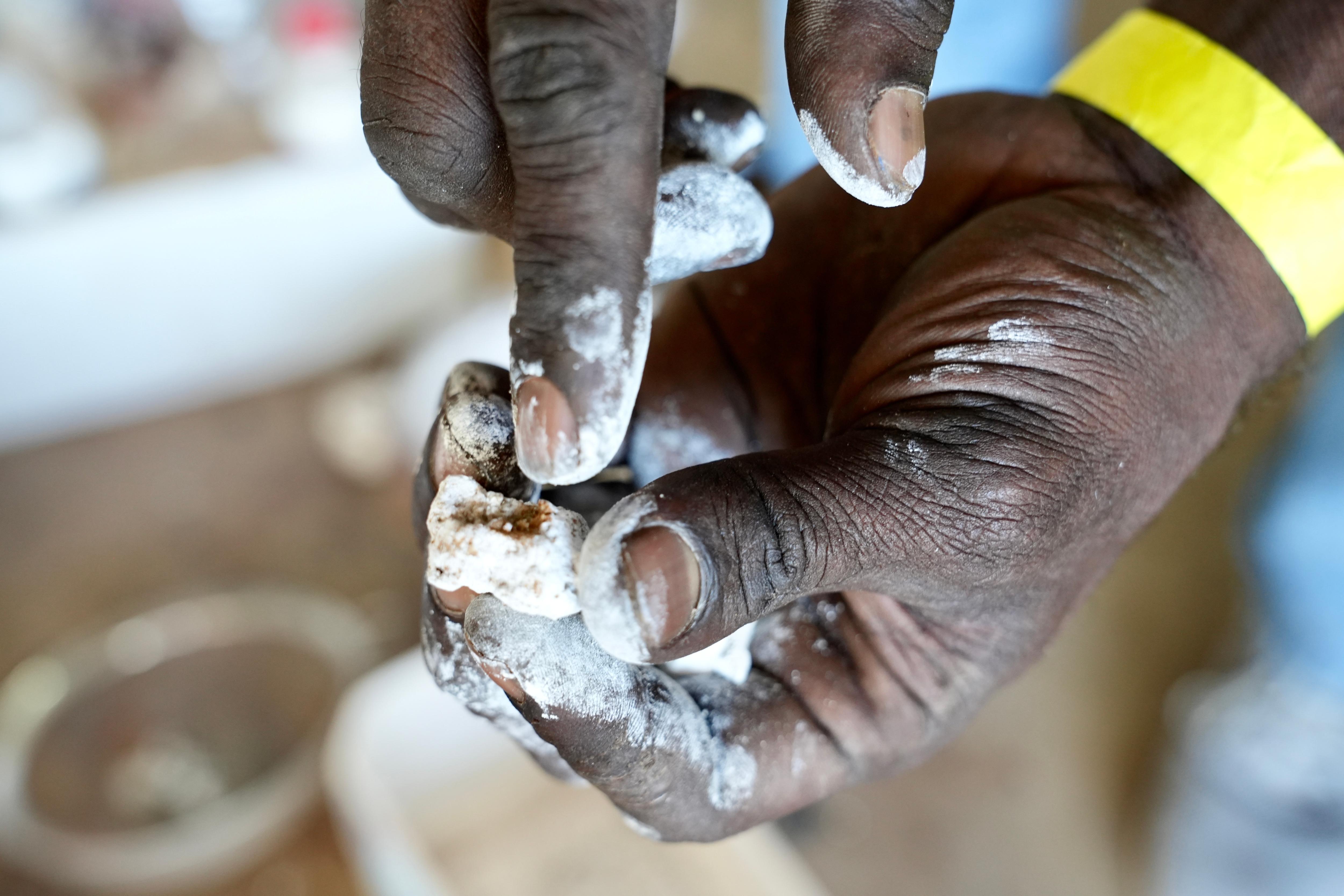 close up of dark hands covered in white ochre