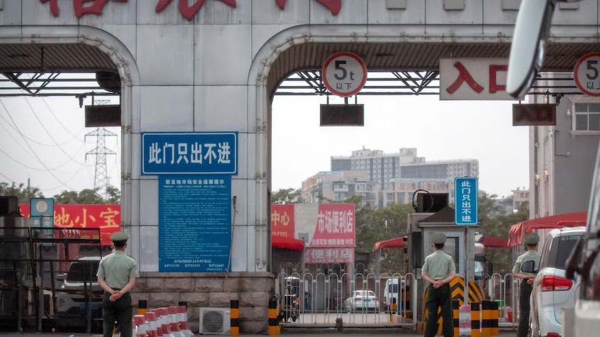 Chinese paramilitary police stand guard at barricaded entrances to the Xinfadi wholesale food market