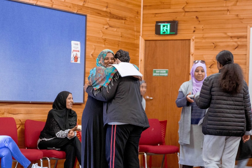 A mother and daughter hug in a workshop.