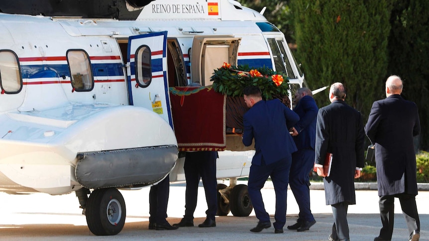 Franco's coffin is slid into a small plane by several men dressed in dark blue