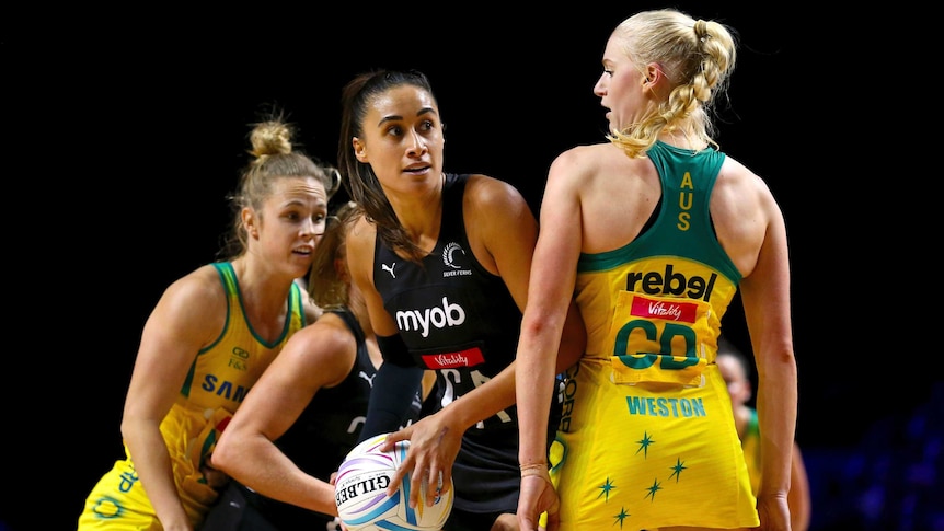 A female netball player looks to pass as an opponent stands next to her.