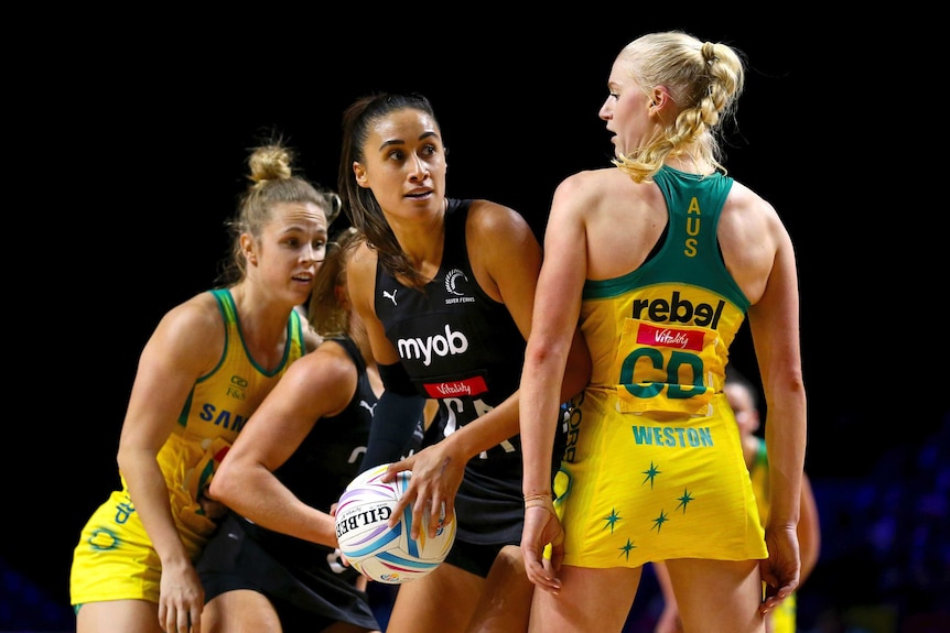 A female netball player looks to pass as an opponent stands next to her.