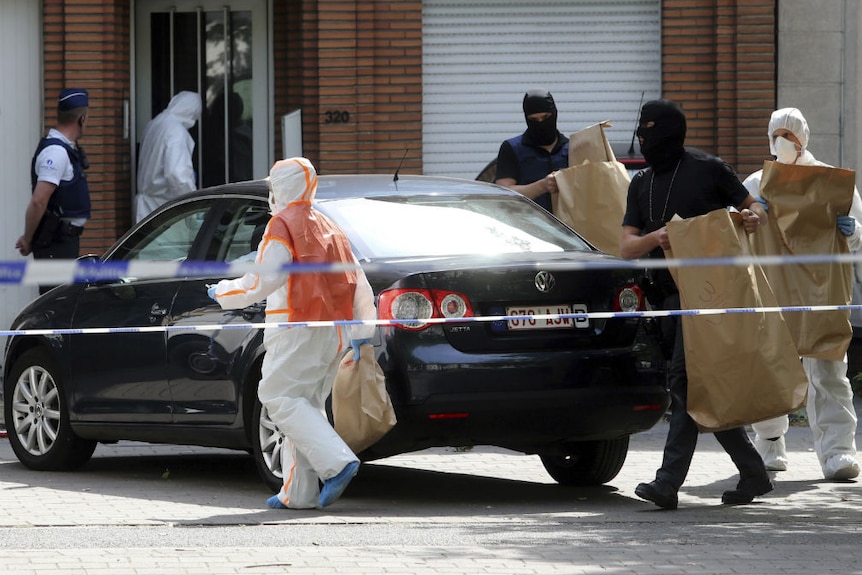 Police and forensic officer raid the house of a suspected Belgian bomber in the district of Molenbeek.