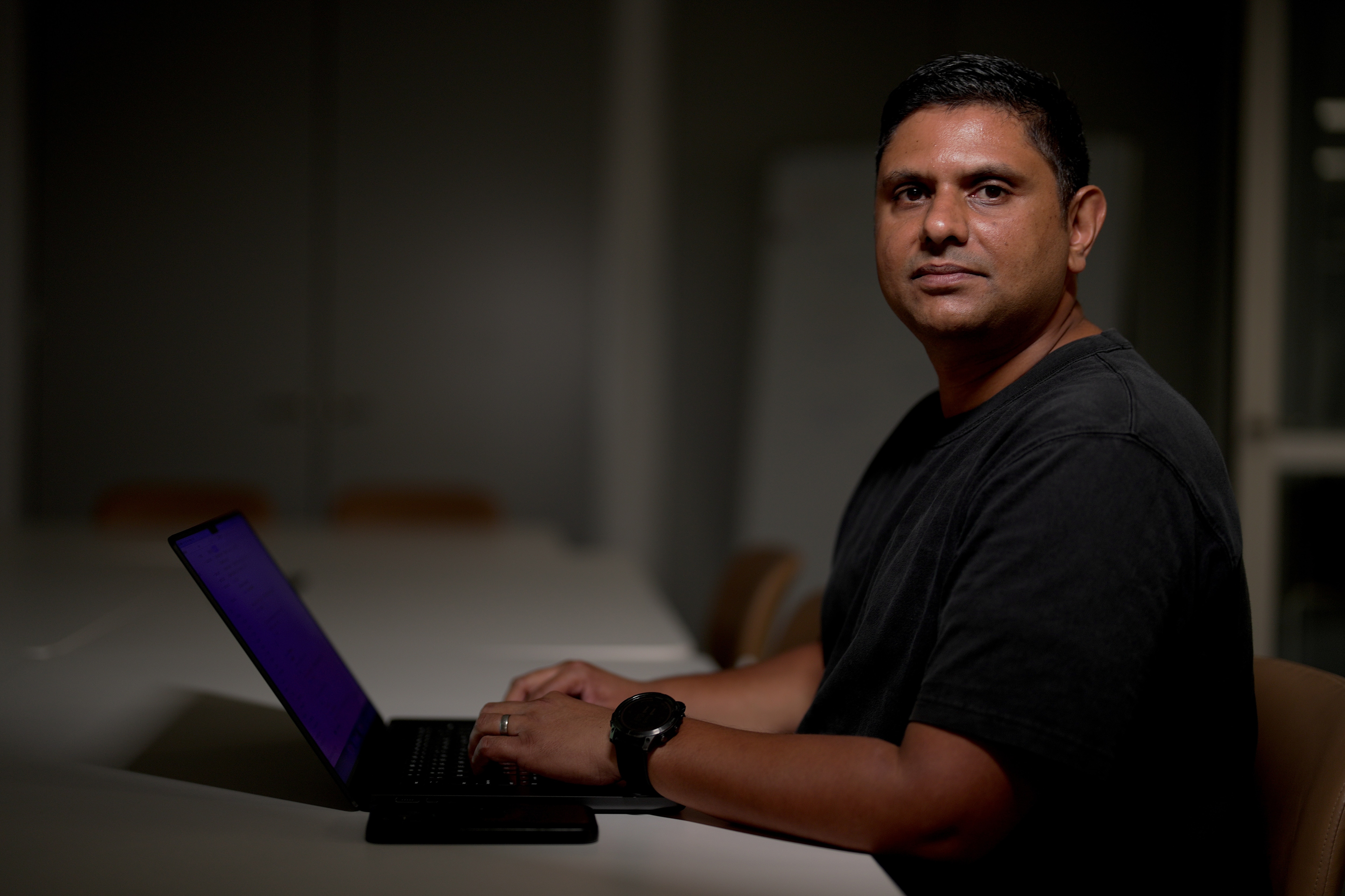 Un hombre sentado en un escritorio con una computadora portátil frente a él.