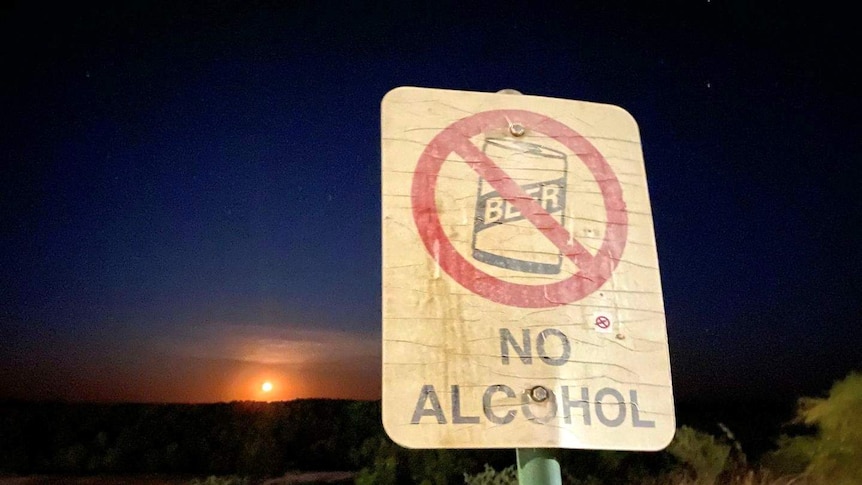 A sign with no alcohol in front of a sunset