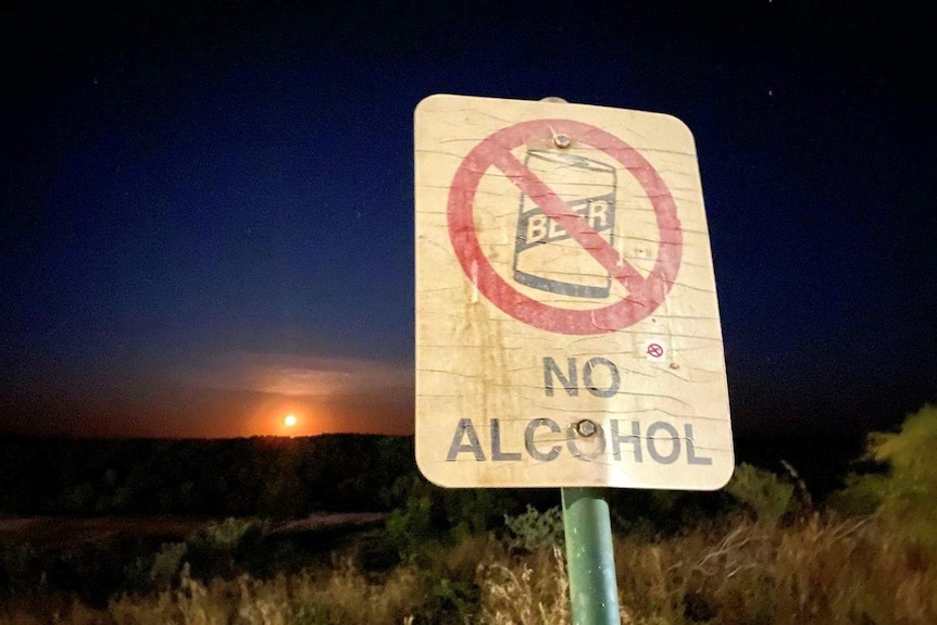 A sign with no alcohol in front of a sunset.
