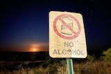 A sign with no alcohol in front of a sunset