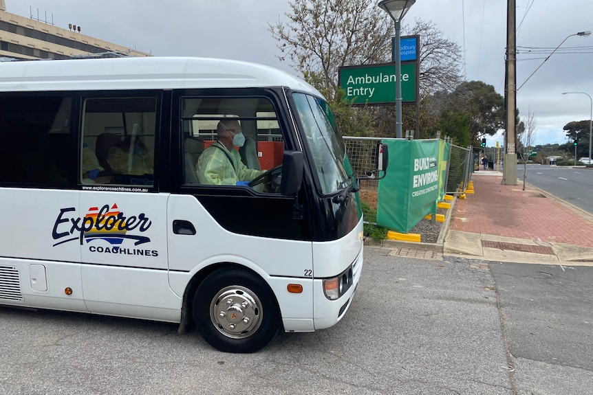 A small bus with a driver wearing a mask