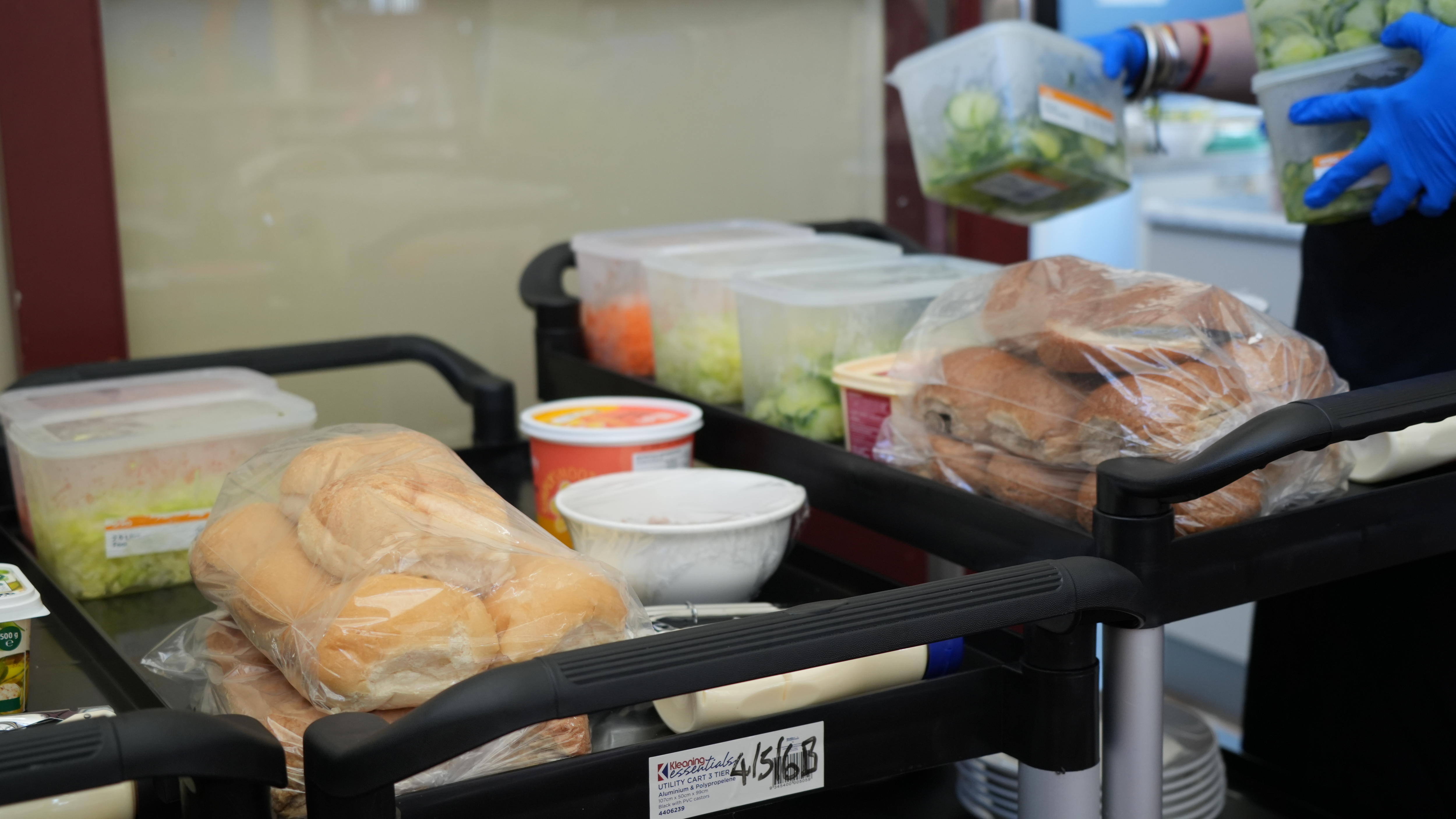 A food trolley containing bread rolls, salads and meats.